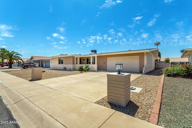 ranch-style home with an attached garage, fence, and concrete driveway