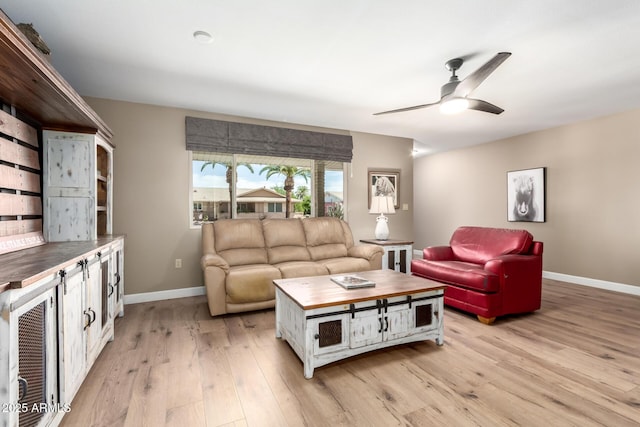 living area featuring light wood-type flooring, baseboards, and ceiling fan