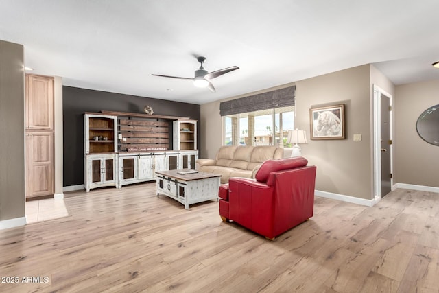 living room featuring light wood-type flooring, a ceiling fan, and baseboards