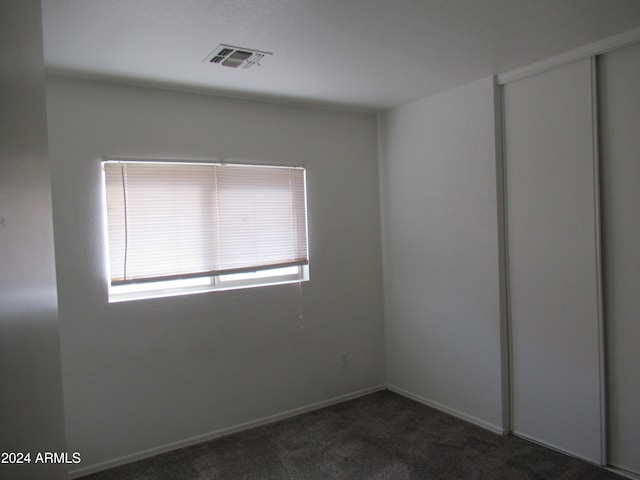 unfurnished room featuring dark carpet