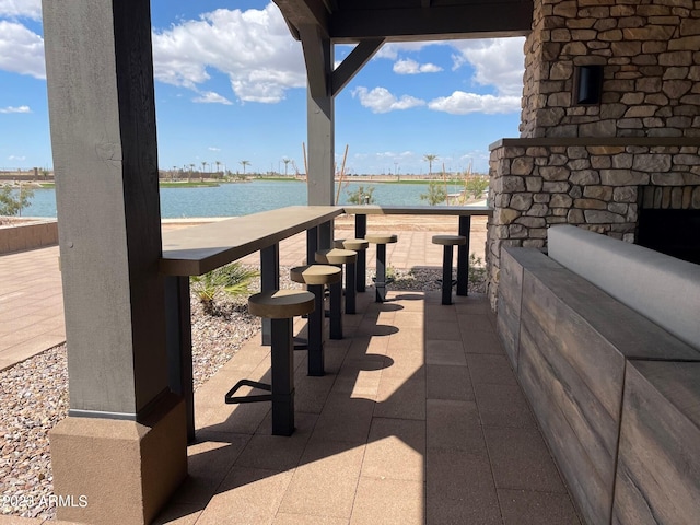 view of patio / terrace with a water view and an outdoor stone fireplace