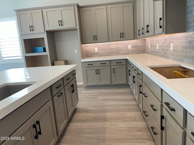 kitchen with gray cabinets, backsplash, and light hardwood / wood-style floors