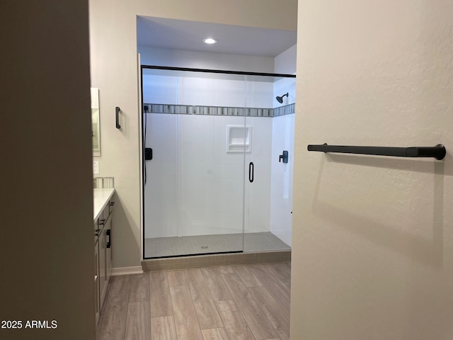 bathroom with wood-type flooring, an enclosed shower, and vanity