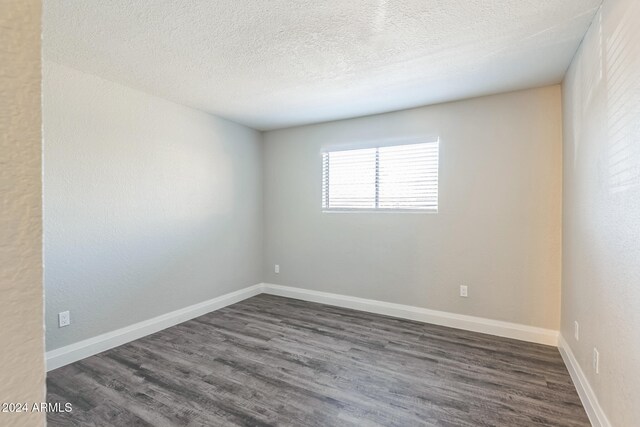 spare room with a textured ceiling and dark hardwood / wood-style floors