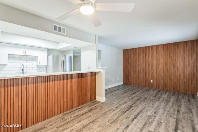 interior space with tasteful backsplash, white cabinetry, ceiling fan, stainless steel refrigerator, and light hardwood / wood-style flooring