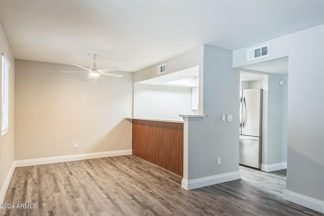 empty room with a wealth of natural light, wood-type flooring, and ceiling fan