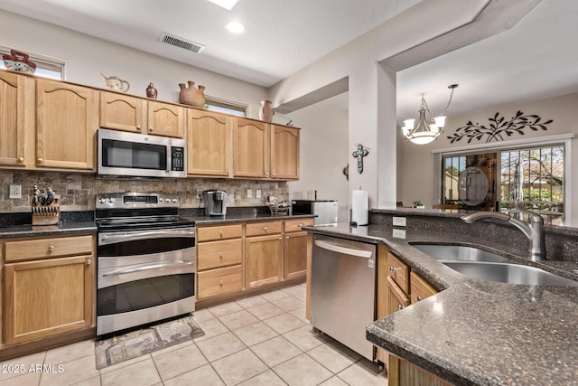 kitchen featuring visible vents, light tile patterned flooring, a sink, appliances with stainless steel finishes, and backsplash