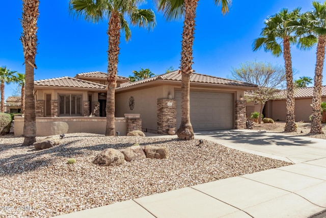 mediterranean / spanish-style house with an attached garage, stucco siding, concrete driveway, stone siding, and a tile roof