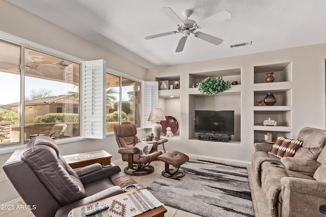 living room featuring visible vents, built in shelves, baseboards, and ceiling fan