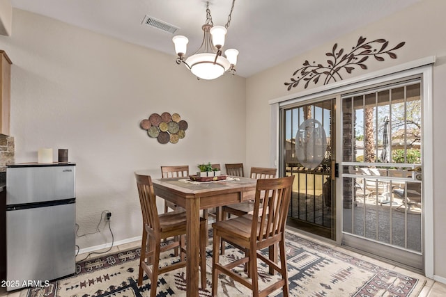 dining area featuring baseboards, visible vents, and a chandelier