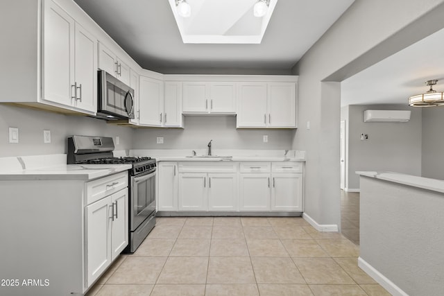 kitchen with stainless steel appliances, a wall mounted AC, white cabinets, and light tile patterned floors