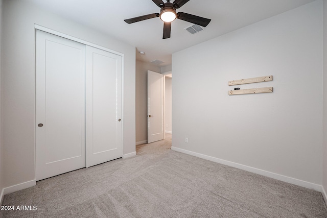 unfurnished bedroom with ceiling fan, light colored carpet, and a closet