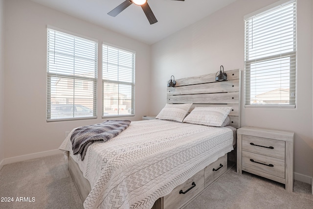 bedroom featuring ceiling fan, light colored carpet, and multiple windows