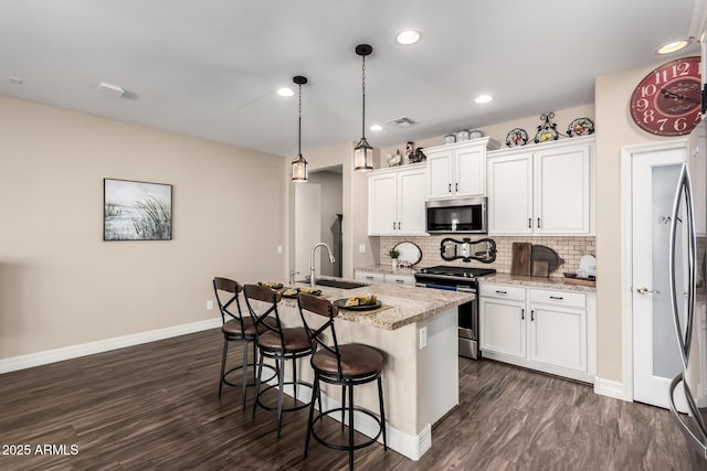 kitchen featuring tasteful backsplash, visible vents, a breakfast bar, appliances with stainless steel finishes, and a sink