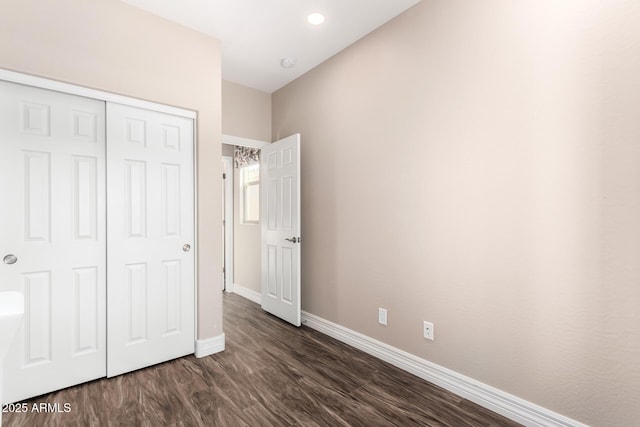 unfurnished bedroom featuring dark wood finished floors, a closet, and baseboards