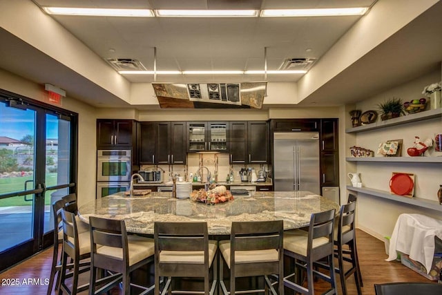 kitchen featuring a breakfast bar area, stainless steel appliances, visible vents, and dark wood-style floors