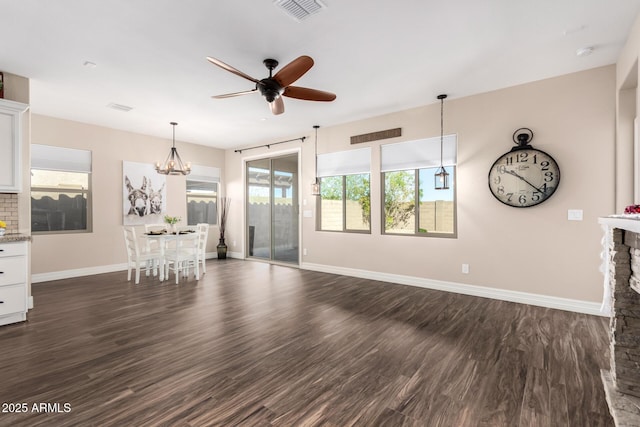 unfurnished living room featuring a ceiling fan, baseboards, visible vents, dark wood finished floors, and a fireplace