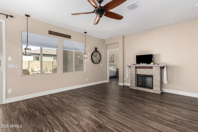 unfurnished living room featuring a ceiling fan, dark wood-style floors, visible vents, baseboards, and a stone fireplace