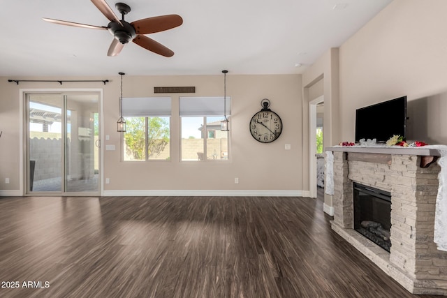 unfurnished living room with baseboards, plenty of natural light, dark wood-style flooring, and a fireplace