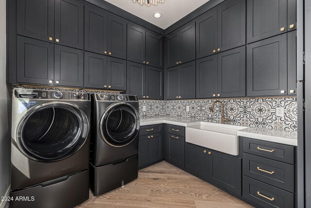 clothes washing area featuring cabinets, light wood-type flooring, separate washer and dryer, and sink