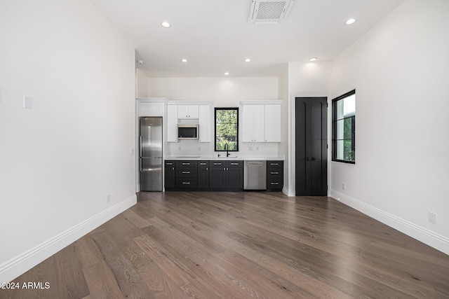 kitchen featuring appliances with stainless steel finishes, dark hardwood / wood-style flooring, white cabinetry, and a healthy amount of sunlight