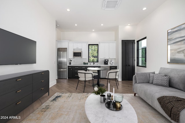 living room featuring sink, light wood-type flooring, and plenty of natural light