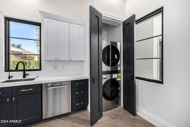 laundry area featuring dark hardwood / wood-style flooring, stacked washer and clothes dryer, and sink