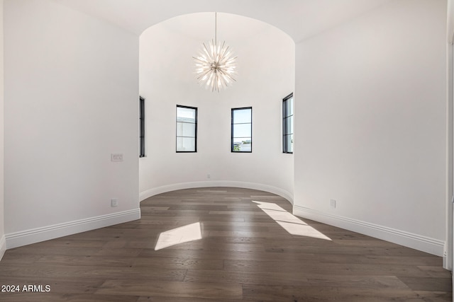 empty room featuring an inviting chandelier and dark wood-type flooring