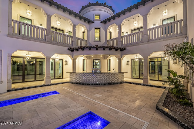 back house at dusk with a patio, a balcony, and sink