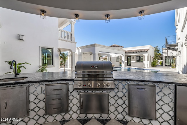 view of patio with area for grilling, a balcony, exterior kitchen, and a wet bar