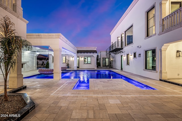 pool at dusk with a jacuzzi and pool water feature