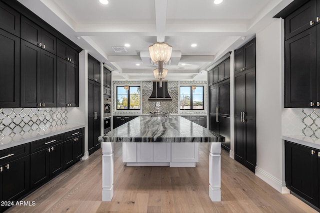 kitchen featuring backsplash, a breakfast bar area, light hardwood / wood-style floors, and coffered ceiling