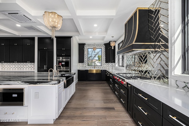 kitchen with decorative backsplash, coffered ceiling, stainless steel appliances, wood-type flooring, and hanging light fixtures