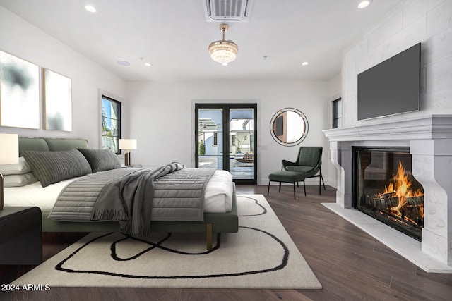 bedroom featuring a large fireplace, access to outside, and dark hardwood / wood-style floors