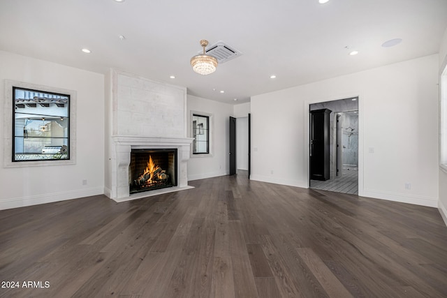 unfurnished living room with dark wood-type flooring and a tiled fireplace