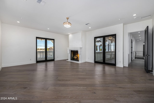 unfurnished living room featuring french doors, dark hardwood / wood-style flooring, and a large fireplace