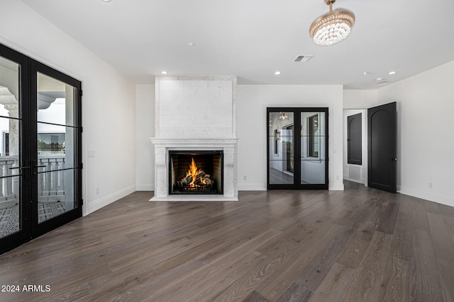 unfurnished living room with french doors, dark hardwood / wood-style flooring, and a large fireplace