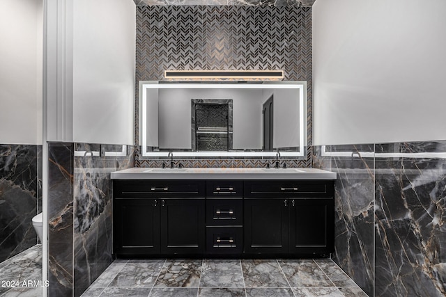 bathroom with vanity, toilet, and tile walls