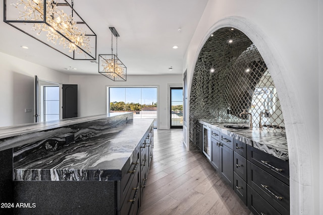 kitchen with a center island, hanging light fixtures, tasteful backsplash, light stone counters, and light hardwood / wood-style floors