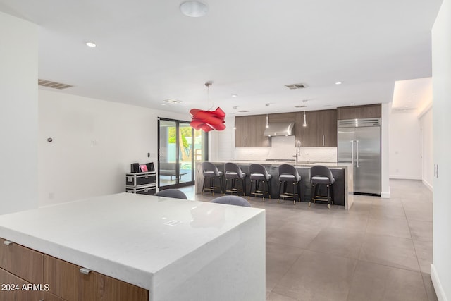 kitchen with stainless steel built in fridge, pendant lighting, a kitchen island, extractor fan, and a kitchen breakfast bar