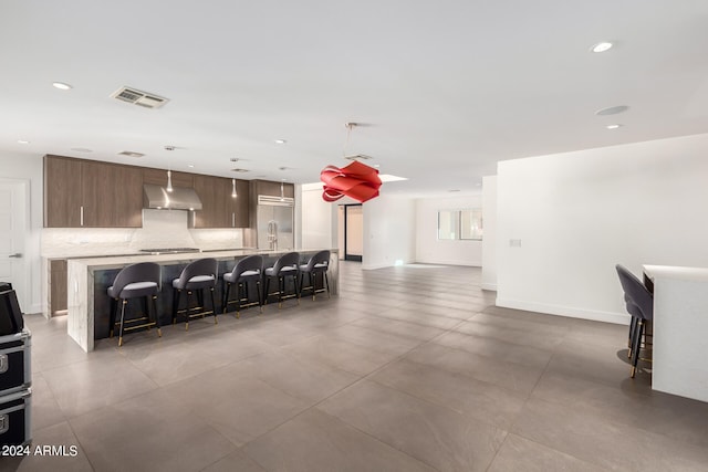 kitchen featuring extractor fan, pendant lighting, a kitchen bar, and a kitchen island with sink