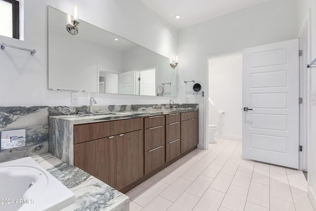 bathroom with vanity, tiled bath, tile patterned flooring, and toilet