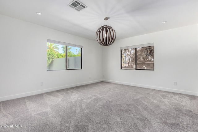 carpeted spare room with a notable chandelier and a wealth of natural light