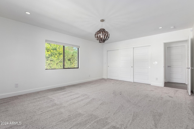 unfurnished bedroom featuring a notable chandelier, a closet, and carpet