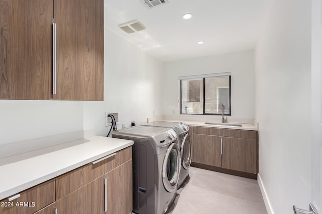 laundry room featuring separate washer and dryer, sink, and cabinets