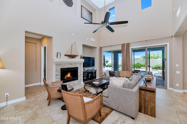 living room with a towering ceiling, a fireplace, and ceiling fan