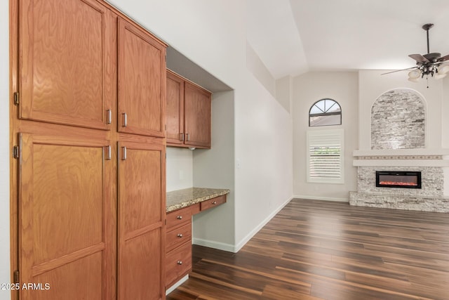 869 W Emerald Island Dr, Gilbert, AZ 85233 - unfurnished living room with vaulted ceiling, dark wood-type flooring, ceiling fan, a glass covered fireplace, and baseboards