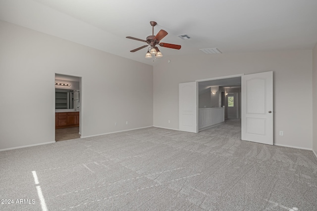 unfurnished bedroom with connected bathroom, light colored carpet, vaulted ceiling, and ceiling fan
