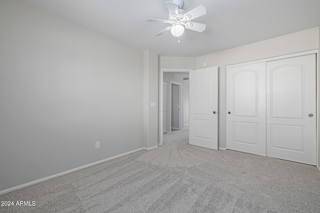 unfurnished bedroom with ceiling fan, a closet, and light carpet