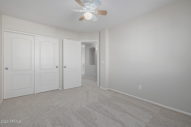 unfurnished bedroom featuring ceiling fan, light carpet, and a closet